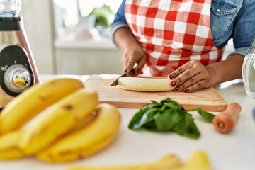 Hispanic brunette woman preparing fruit smoothie at the kitchen