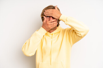 blond adult man covering face with both hands saying no to the camera! refusing pictures or...