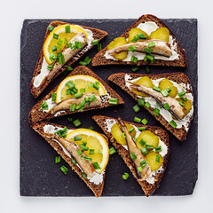 canapes with sprats on a black stone tray