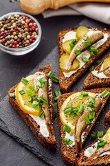 canapes with sprats on a black stone tray