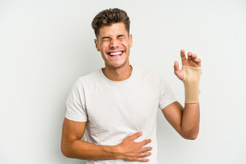 Young caucasian man hand sling isolated on white background laughing and having fun.