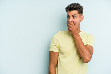 Fototapeta premium Young caucasian man isolated on blue background thoughtful looking to a copy space covering mouth with hand.