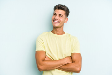 Young caucasian man isolated on blue background dreaming of achieving goals and purposes