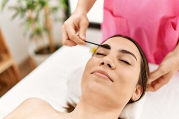 Obraz na płótnie Canvas Young hispanic woman smiling confident having eyebrows treatment at beauty center.