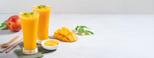 Fresh beautiful delicious mango juice smoothie in glass cup on gray table background.