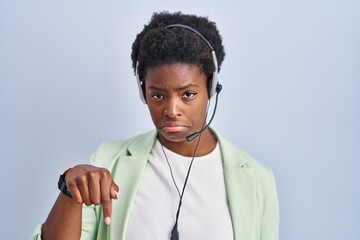 African american woman wearing call center agent headset pointing down looking sad and upset,...