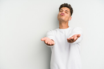 Young caucasian man isolated on white background folding lips and holding palms to send air kiss.