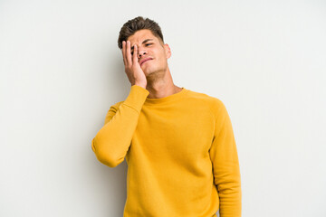 Young caucasian man isolated on white background tired and very sleepy keeping hand on head.