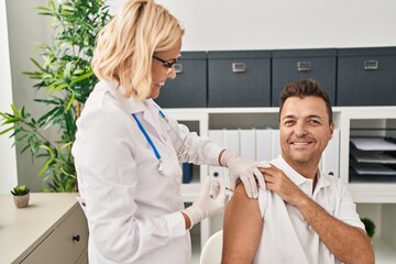 Middle age man and woman doctor and patient vaccinating at clinic