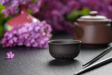 Brown ceramic asian teapot , tea cups and chopsticks on background of purple flowers. Japanese food concept