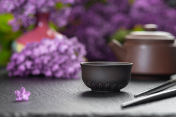 Brown ceramic asian teapot , tea cups and chopsticks on background of purple flowers. Japanese food concept