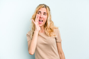 Young caucasian woman isolated on blue background shouting excited to front.