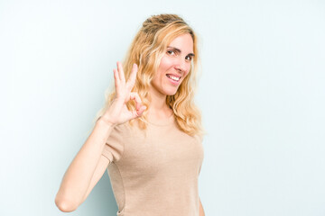 Young caucasian woman isolated on blue background cheerful and confident showing ok gesture.