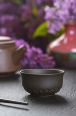 Brown ceramic asian teapot , tea cups and chopsticks on background of purple flowers. Japanese food concept