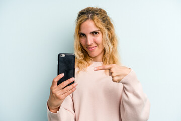 Fototapeta premium Young caucasian woman holding mobile phone isolated on blue background