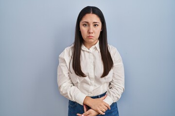 Young latin woman standing over blue background depressed and worry for distress, crying angry and afraid. sad expression.