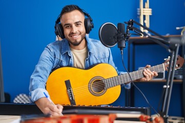 Young hispanic man artist composing song playing classical guitar at music studio