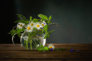 bouquet of summer flowers in  glass teapot on  dark background,  concept of healthy herbal tea © Maya Kruchancova