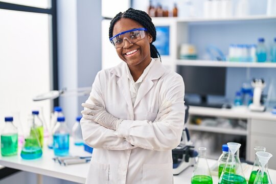 African american woman working at scientist laboratory happy face smiling with crossed arms looking at the camera. positive person.