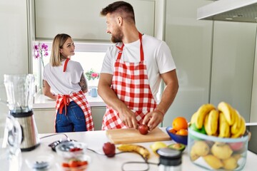 Young couple smiling confident making smoothie cooking at kitchen