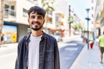 Young hispanic man smiling happy standing at the city.