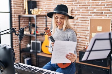 Fototapeta na wymiar Young woman artist holding ukelele reading song at music studio