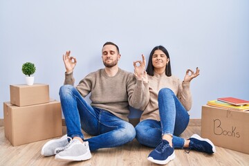 Young couple moving to a new home relaxed and smiling with eyes closed doing meditation gesture with fingers. yoga concept.