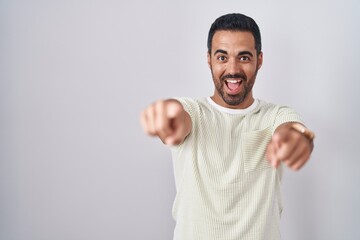 Fototapeta premium Hispanic man with beard standing over isolated background pointing to you and the camera with fingers, smiling positive and cheerful