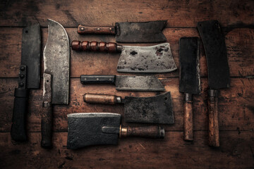 flat lay picture set of old rusty carbon steel cleavers on top of wooden table