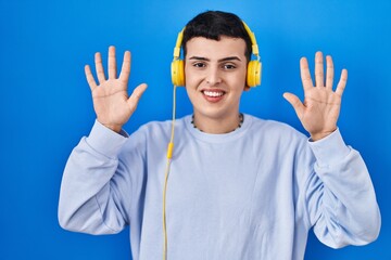 Non binary person listening to music using headphones showing and pointing up with fingers number ten while smiling confident and happy.