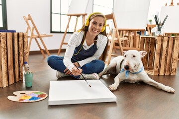 Young caucasian woman listening to music drawing with dog at art studio
