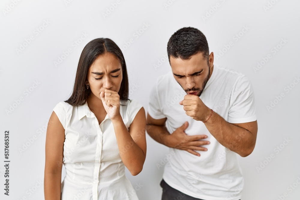 Sticker Young interracial couple standing together in love over isolated background feeling unwell and coughing as symptom for cold or bronchitis. health care concept.