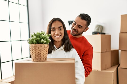 Young latin couple smiling happy holding cardboard box at new home.