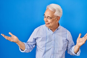 Hispanic senior man wearing glasses smiling showing both hands open palms, presenting and advertising comparison and balance