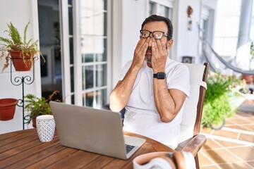 Middle age man using computer laptop at home rubbing eyes for fatigue and headache, sleepy and...