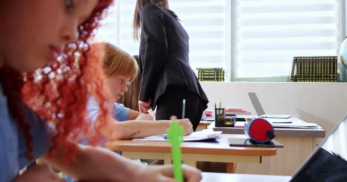 Caucasian young woman teacher of biology taking and colecting papers with tests from pupils. Exams at school. Examination concept. Biological or chemistry test for kids at class. Education.