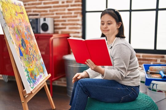 Young woman with down syndrome artist reading book drawing at art studio