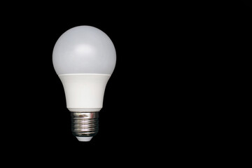 Energy saving light bulb on a black background with free space for text. Saving energy and finances. Electrical equipment and the evolution of light. Free space for text