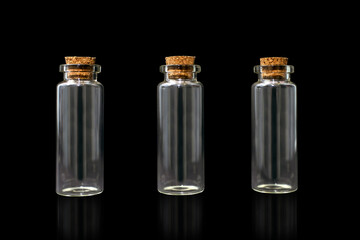 Three empty glass bottles on a black background with corks. Glass vessels for various liquids. Set of identical closed test tubes on a black background