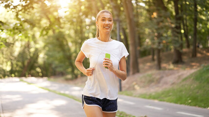 Woman putting on earphones to listen music before jogging summer park