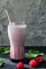 Delicious raspberry cocktail with yogurt on a dark background and fresh raspberries next to it, copy space