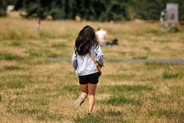 A young woman runs over a meadow in Berlin-Germany on a warm and sunny day.