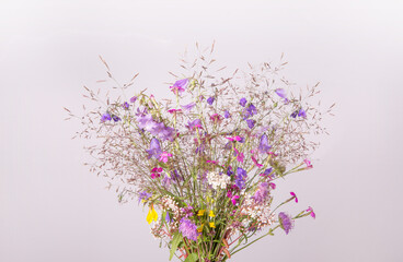 Obraz na płótnie Canvas Festive bouquet of yellow and purple, blue wildflowers, herbs on gray background. Birthday, Mother's, Valentines, Women's, Wedding Day concept.