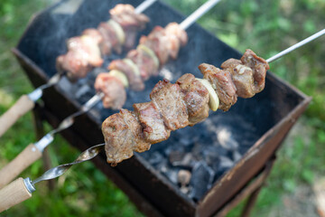 Grilled shish kebab is on the skewer. On the background of the barbecue with barbecue. local focus.