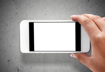 A hand hold phone against a light stone wall.