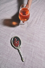 Hand in Vintage Mirror and Woman hand holding Glass of Rose Wine
