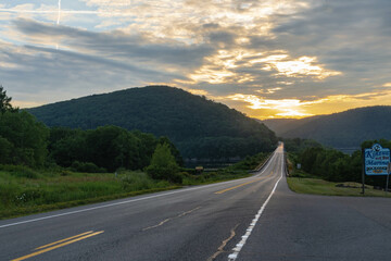 Summer road trip with setting sun in mountain scenery 