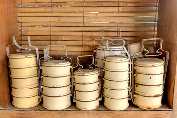 Close-up of  many old useless yellow tiffins on Bamboo background