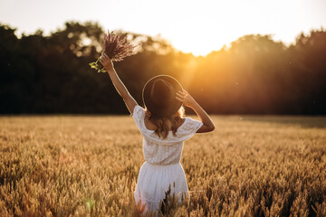 Happy girl in a hat in a wheat field looks at the sunset © sushytska