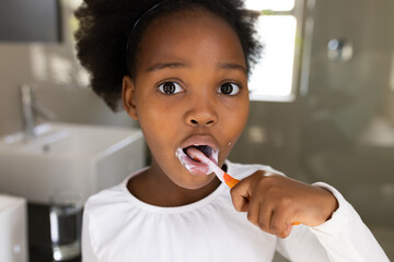 Image of african american girl brushing teeth